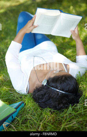 Étudiant insouciant de la révision et à l'écoute de musique dans le parc Banque D'Images