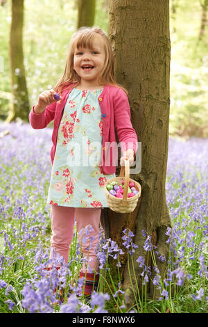 Fille sur la chasse aux Œufs de Pâques dans la région de Bluebell Woods Banque D'Images