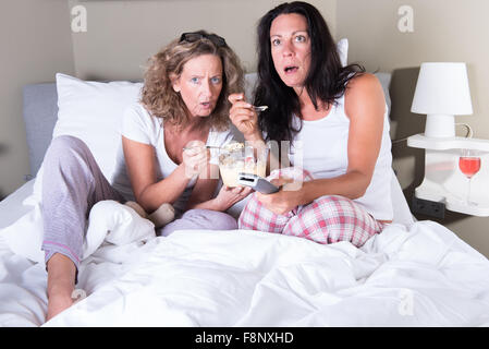 Deux attratcive women sitting in bed et l'affichage plat Banque D'Images