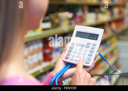 Woman Using Calculator tout en Shopping in Supermarket Banque D'Images