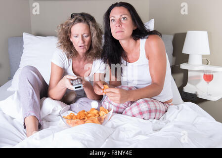 Deux attratcive women sitting in bed et l'affichage plat Banque D'Images