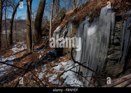 La fonte de la dérive vers le bas d'une colline puis regèle froid sur des rochers près de la rivière Susquehanna en Pennsylvanie. Banque D'Images