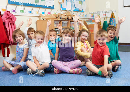 Groupe d'élèves de l'élémentaire mettant les mains en classe Banque D'Images