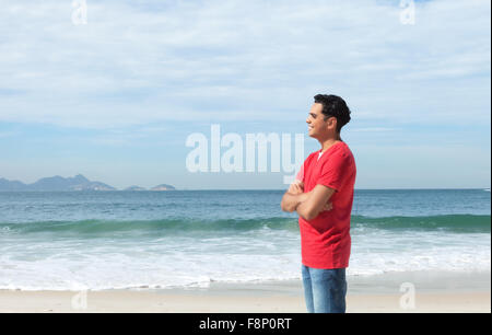 Guy standing d'Amérique latine à la plage et à la recherche à l'océan Banque D'Images