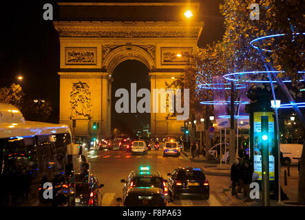 Les voitures roulent autour de la base de l'Arc de Triomphe de nuit à Paris, France Banque D'Images