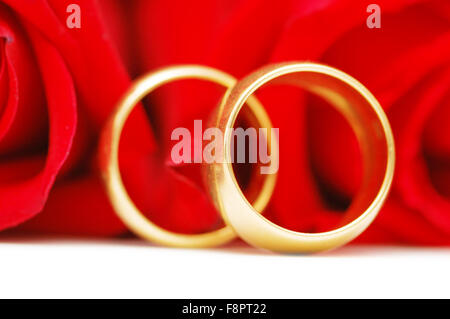 Deux anneaux de mariage d'or et roses rouges Banque D'Images