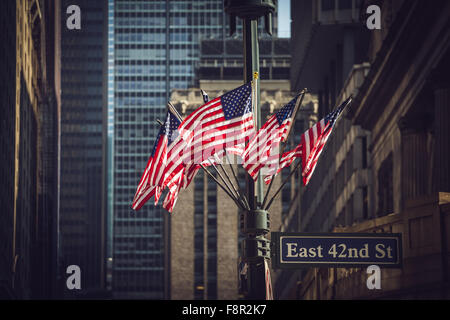 New York City - 19 septembre : Manhattan, des drapeaux américains sur une colonne avec East 42nd Street sign le 19 septembre 2015. Banque D'Images