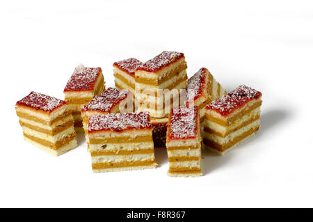 Close-up de dix pièces de délicieux gâteau éponge multicouche et crème anglaise, avec glaçage rouge et noix de coco, sur une ontop sprinkles b blanc Banque D'Images