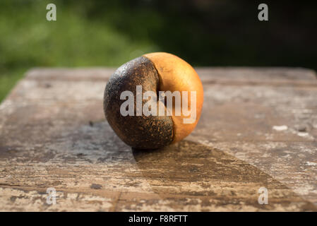 La moitié de pomme pourrie sur une table en bois Banque D'Images