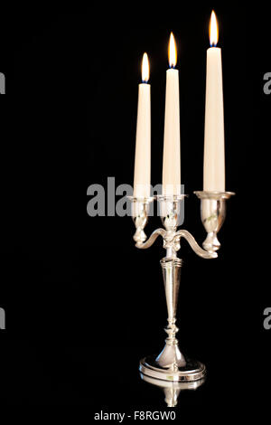 Chandelier en argent avec gravure trois bougies blanches en face de fond noir Banque D'Images