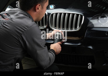 Rédaction d'illustration. Le travailleur polit une voiture avec le pare-choc de bord outil électrique. Service de voiture 'Aquacars'. Moscou. 04.10.2015 Banque D'Images