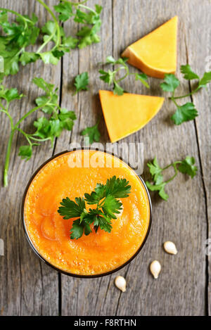 Smoothie à la citrouille dans un verre, tranches et les herbes sur fond de bois, vue du dessus Banque D'Images