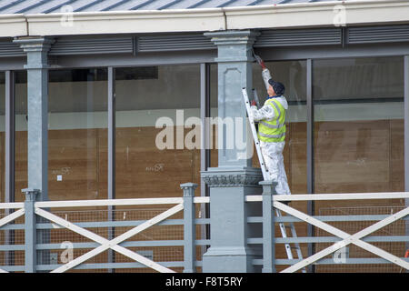 Un peintre et décorateur peint un pilier sur Town Pier à Gravesend, dans le Kent. Banque D'Images