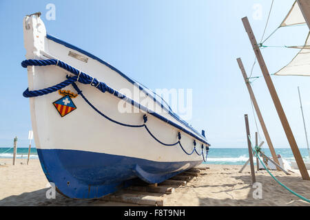 Calafell, Espagne - 20 août 2014 : bateau de pêche en bois blanc s'étend sur une plage de sable, mer Méditerranée, côte de l'Espagne Banque D'Images