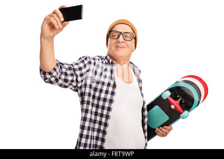 Patineur Senior holding a skateboard et prendre une avec son téléphone cellulaire selfies isolé sur fond blanc Banque D'Images