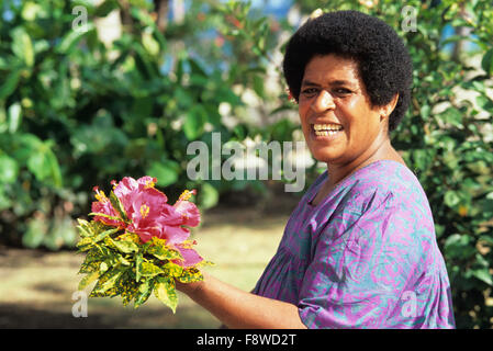 Les Fidji, Yasawa Island Resort, Yasawa Isalnd, personnel féminin à la cueillette des fleurs pour des accords qui doivent être placés à Bure. Banque D'Images