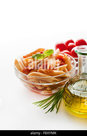 Pâtes penne à la sauce tomate au basilic décorée sur un fond blanc. Banque D'Images