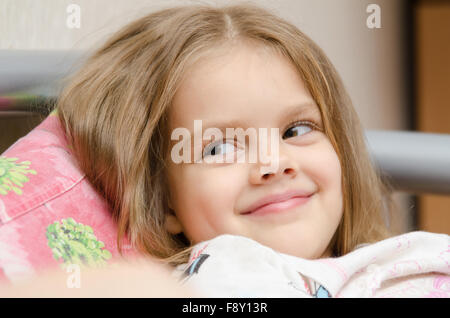 Cheerful fille de cinq ans couché sur le lit et regarda à gauche smorit Banque D'Images