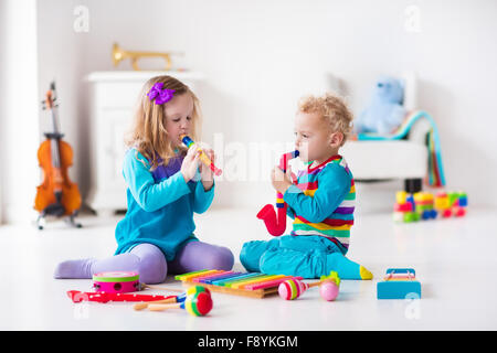 Les enfants avec des instruments de musique. L'éducation musicale pour les enfants. Art toys en bois coloré. Petite fille et garçon de jouer de la musique. Banque D'Images