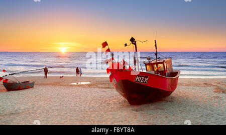 Bateau de pêche sur la plage près de la mer Baltique, Miedzyzdroje, Pologne, au coucher du soleil Banque D'Images