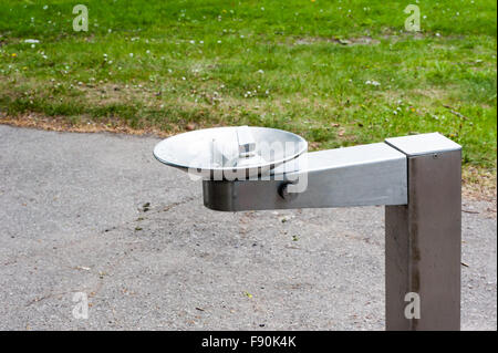 Silver metal vide eau eau potable fontaine située près de sentier du parc et de l'herbe. Banque D'Images