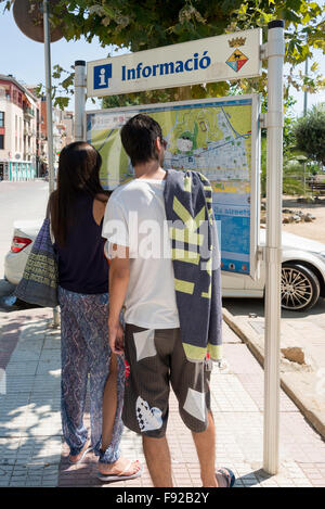 Couple looking at resort information board, Calella, Costa del Maresme, Province de Barcelone, Catalogne, Espagne Banque D'Images