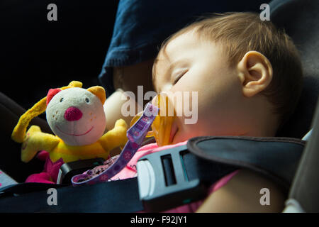 9 mois bébé fille dormir dans le siège d'auto avec sa marionnette