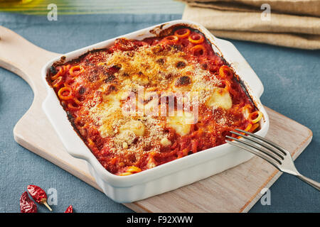 Anelletti au four avec petits pâtes, la sauce et de la mozzarella. Sicilienne typique plat de pâtes avec sauce tomate, viande hachée et fromage, cuit au four Banque D'Images