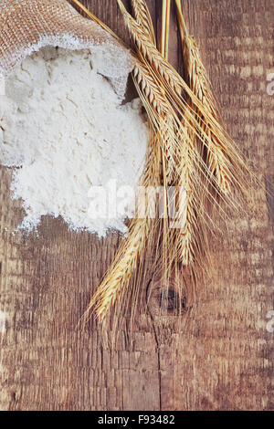 Sac sac de farine blanche avec les épis de blé sur fond de bois Banque D'Images