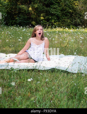 Une jeune femme le bâillement dans un champ de fleurs. Banque D'Images