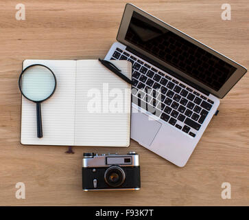 L'ordinateur portable, a ouvert le bloc-notes, loupe et vintage film appareil posé sur une table en bois. Banque D'Images