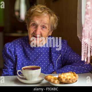 Femme âgée de boire du thé avec des gâteaux. Banque D'Images