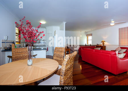 Salon avec canapés en cuir rouge et un coin repas avec table ronde en bois logés dans la même chambre Banque D'Images