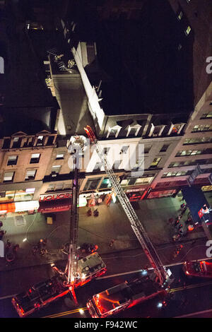 New York, USA. 13 Décembre, 2015. Les camions de l'échelle et de crochet sont sur les lieux avec les pompiers sur le toit d'un immeuble brownstone. Credit : Patti McConville/Alamy Live News Banque D'Images