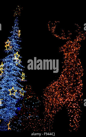 Chevreuil jaune et blanc avec Snowman Christmas Tree Lights Abstract Vertical isolé sur fond noir Banque D'Images