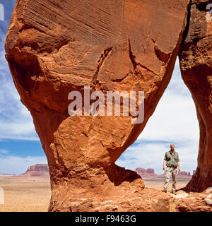 randonneur (autoportrait) debout dans l'arche en forme de goutte d'eau au-dessus de la vallée du monument dans le parc tribal navajo près de la frontière arizona-utah Banque D'Images