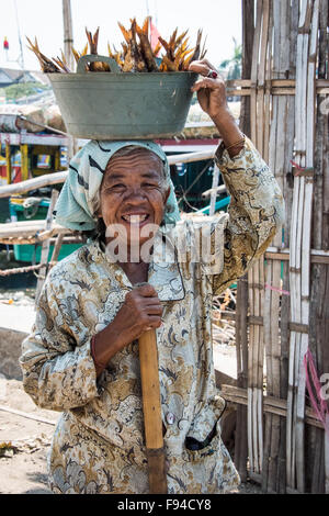 Dame transport du poisson dans le récipient sur la tête, Surabaya, Indonésie Banque D'Images