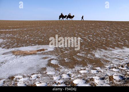 Jiuquan, province du Gansu en Chine. 13 Décembre, 2015. Les gens chameaux visiter le paysage du lac Crescent en place de montagne Mingsha Dunhuang, ville du nord-ouest de la Chine la province de Gansu, le 13 décembre 2015. © Zhang Xiaoliang/Xinhua/Alamy Live News Banque D'Images