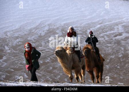 Jiuquan, province du Gansu en Chine. 13 Décembre, 2015. Les gens chameaux visiter le paysage du lac Crescent en place de montagne Mingsha Dunhuang, ville du nord-ouest de la Chine la province de Gansu, le 13 décembre 2015. © Zhang Xiaoliang/Xinhua/Alamy Live News Banque D'Images