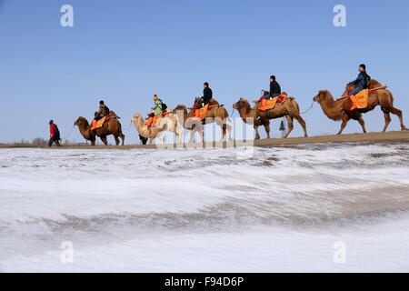 Jiuquan, province du Gansu en Chine. 13 Décembre, 2015. Les gens chameaux visiter le paysage du lac Crescent en place de montagne Mingsha Dunhuang, ville du nord-ouest de la Chine la province de Gansu, le 13 décembre 2015. © Zhang Xiaoliang/Xinhua/Alamy Live News Banque D'Images