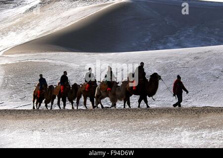 Jiuquan, province du Gansu en Chine. 13 Décembre, 2015. Les gens chameaux visiter le paysage du lac Crescent en place de montagne Mingsha Dunhuang, ville du nord-ouest de la Chine la province de Gansu, le 13 décembre 2015. © Zhang Xiaoliang/Xinhua/Alamy Live News Banque D'Images