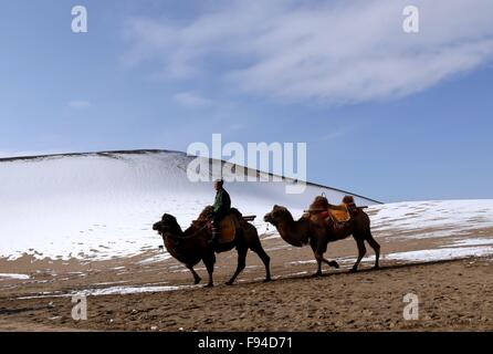 Jiuquan, province du Gansu en Chine. 13 Décembre, 2015. Les gens chameaux visiter le paysage du lac Crescent en place de montagne Mingsha Dunhuang, ville du nord-ouest de la Chine la province de Gansu, le 13 décembre 2015. © Zhang Xiaoliang/Xinhua/Alamy Live News Banque D'Images