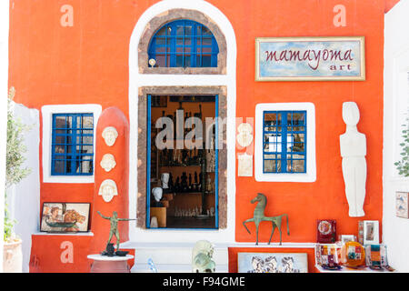 Santorin, Oia. Shop/Mamayoma, art shop, orange peint avec center porte entre deux fenêtres encadrées blanc et bleu. Certains produits à l'extérieur. Banque D'Images