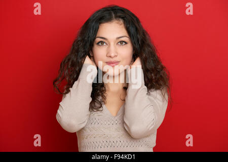 Belle jeune femme portrait avec black long cheveux bouclés sur rouge Banque D'Images