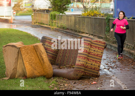 La vie revient à la normale. Canapé endommagé par une inondation et président de Hardwicke Circus à Carlisle, Cumbria, avec un jogger passé en courant le mardi 8 décembre 2015, après une pluie torrentielle de storm Desmond. La tempête a établi un nouveau record britannique pour rainfsll totaux dans une journée avec 341.4mm en 24 heures. Banque D'Images