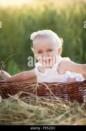 Cute little girl sitting in basket en été nature Banque D'Images