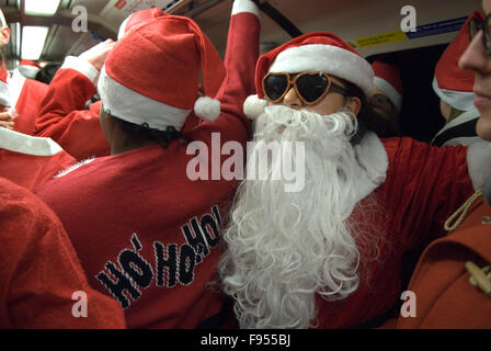 Santa Claus Clauss avec une grande fausse barbe fait partie de la nouvelle tradition annuelle SantaCon. Voyage au lieu de rencontre de l'événement sur le métro londonien HOMER SYKES des années 2015 2010 Banque D'Images