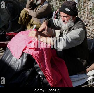 Kaboul, Afghanistan. 14 Décembre, 2015. Un Afghan coiffure coupe de cheveux d'un client dans une rue de Kaboul, capitale de l'Afghanistan, le 14 décembre 2015. Barbershop routière est encore populaire en Afghanistan même dans la capitale, Kaboul. © Rahmat Alizadah/Xinhua/Alamy Live News Banque D'Images