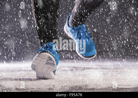 Femme de l'athlète est en cours d'exécution au cours de la formation en dehors de l'hiver dans la neige froide température. Banque D'Images