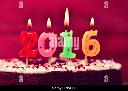 Quatre gros plan numéro allumé des bougies en forme de différentes couleurs formant le nombre 2016, comme la nouvelle année, sur un gâteau Banque D'Images